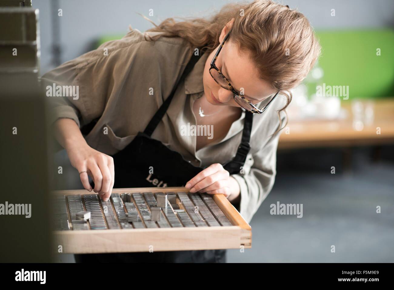 Woman choosing letterpress from tray in print workshop Stock Photo