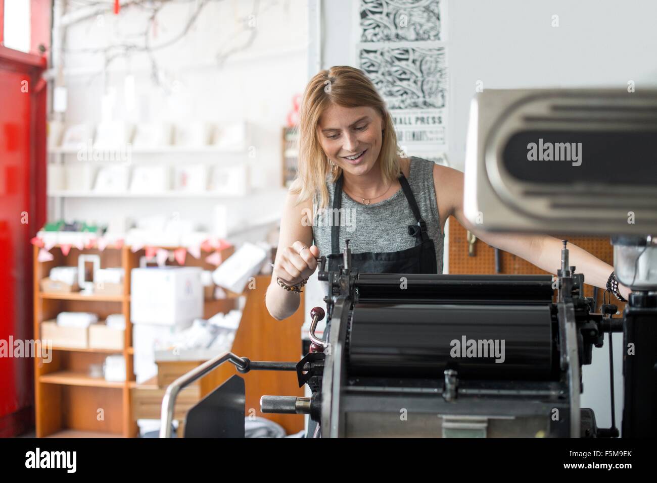 Young woman working on traditional letterpress print machine in workshop Stock Photo