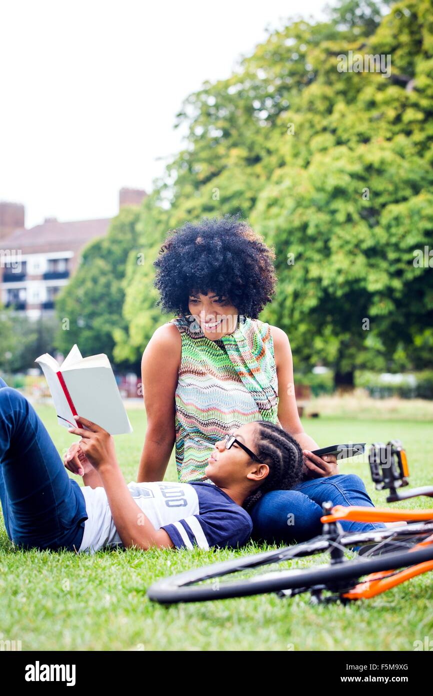 Boy and mother relaxing and reading in park Stock Photo