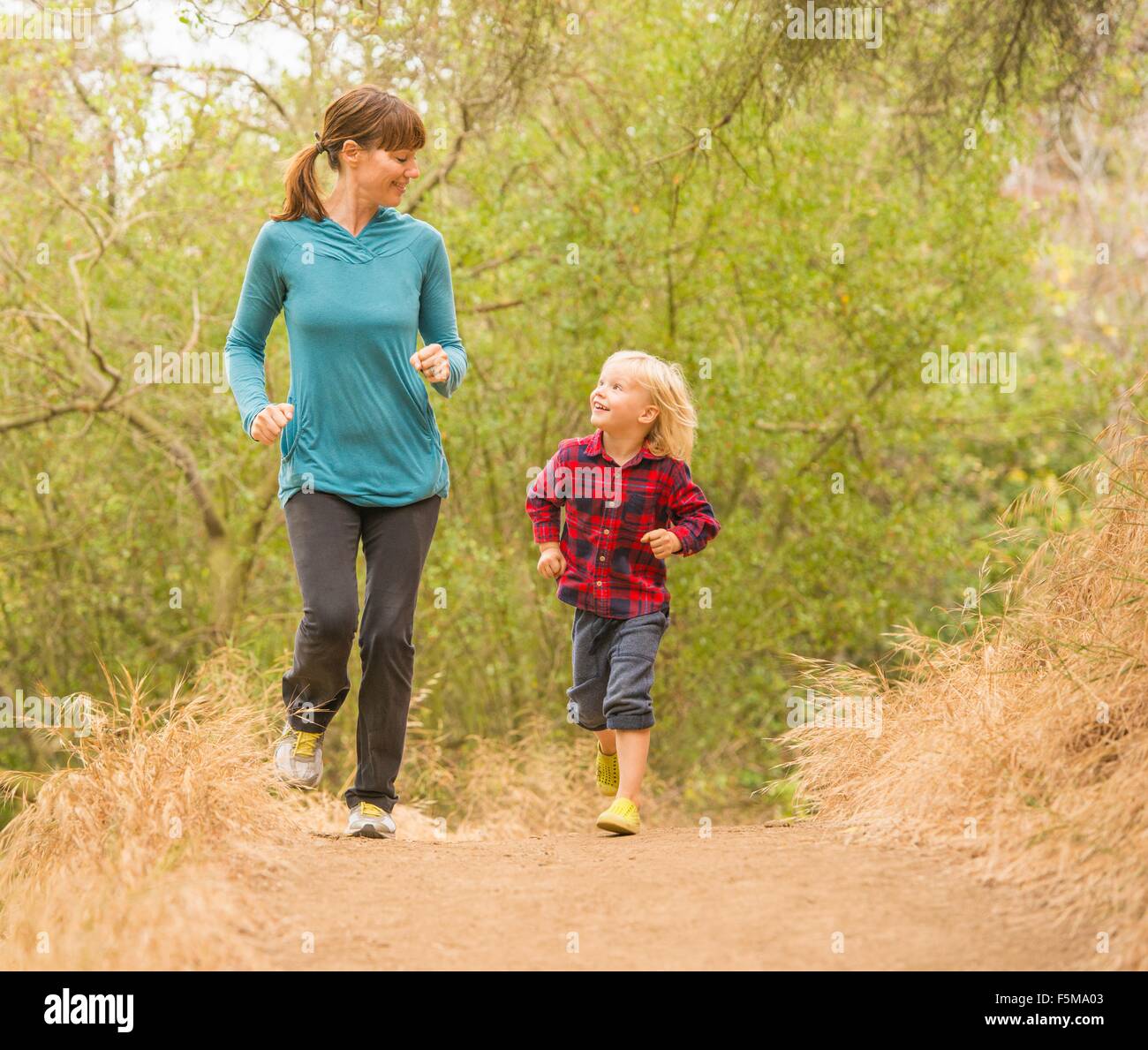 Mother and son running in forest Stock Photo