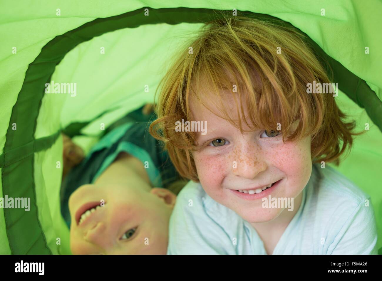 Two young boys playing in play tube Stock Photo - Alamy