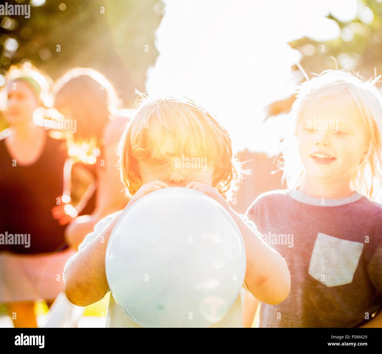 Young boy blowing up balloon in garden Stock Photo