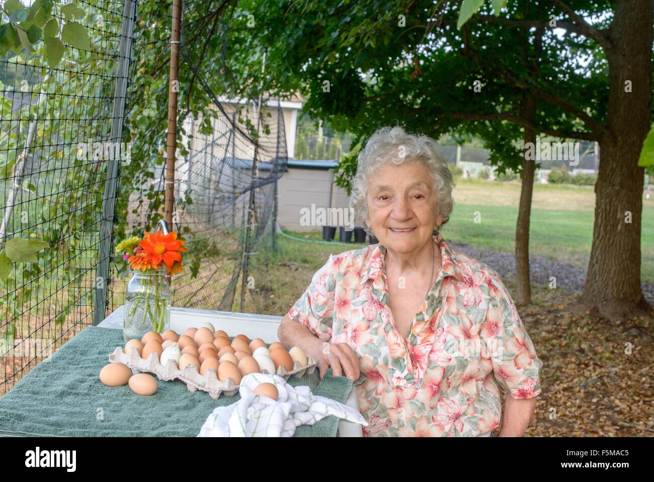 Senior woman posing beside tray of eggs on farm Stock Photo