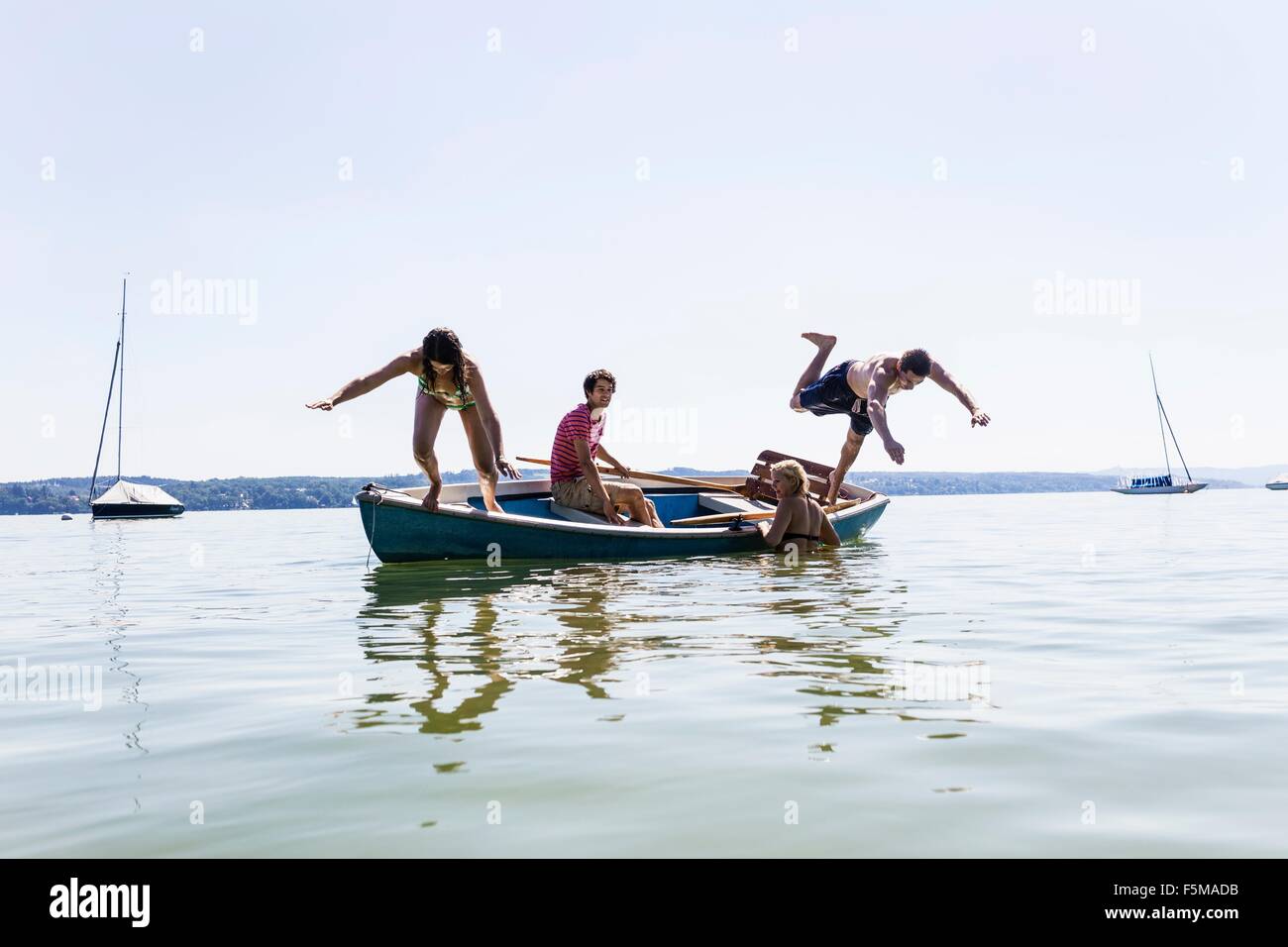 Group of friends diving from boat into lake, Schondorf, Ammersee, Bavaria, Germany Stock Photo