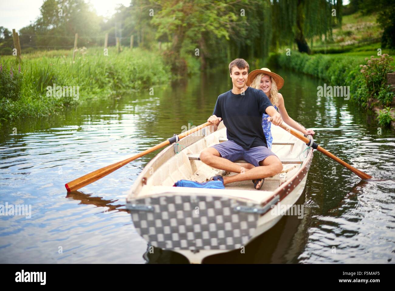 Portrait of young couple rowing on rural river Stock Photo