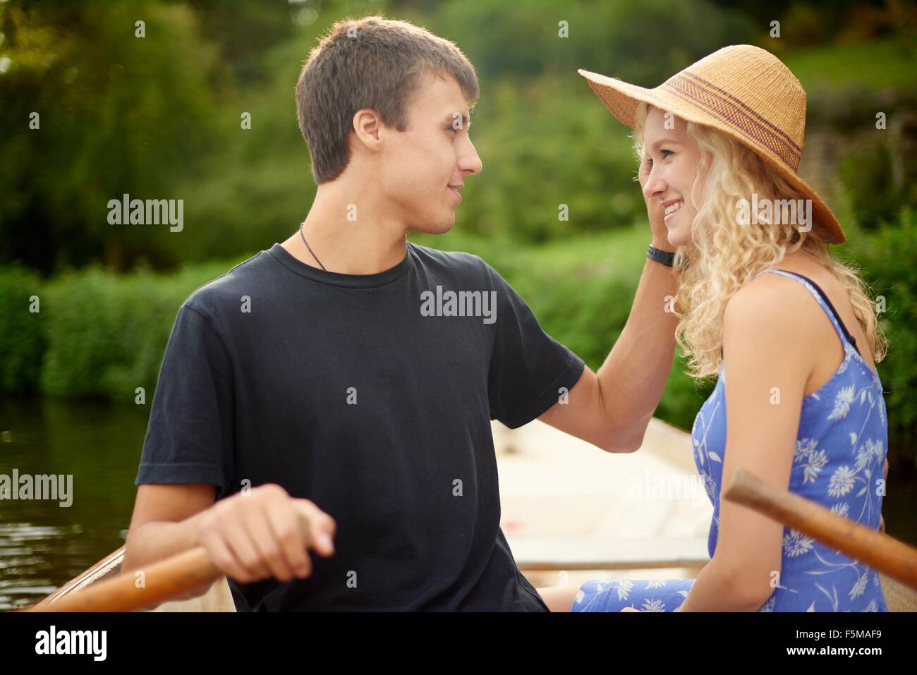 Romantic young couple rowing boat on rural river Stock Photo