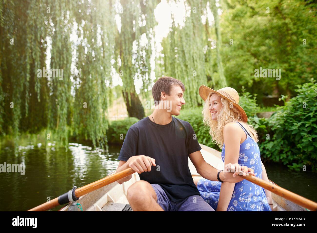 Romantic young couple in rowing boat on rural river Stock Photo
