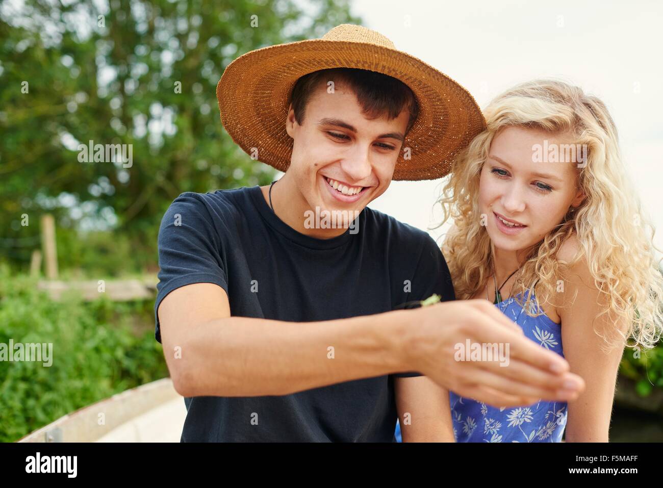 Young couple looking at insect in river rowing boat Stock Photo