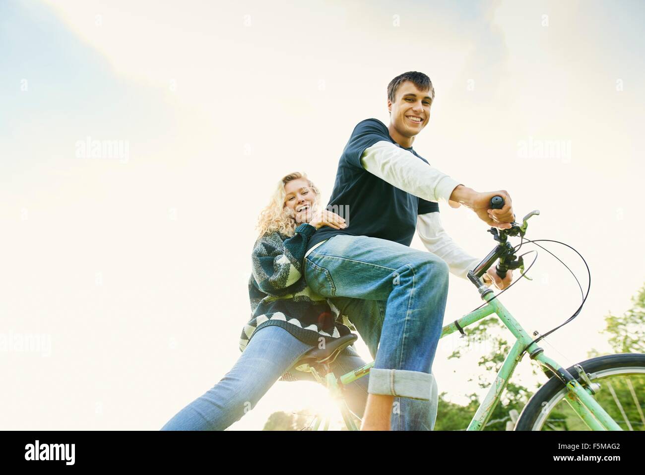Low angle portrait of young couple on bicycle Stock Photo