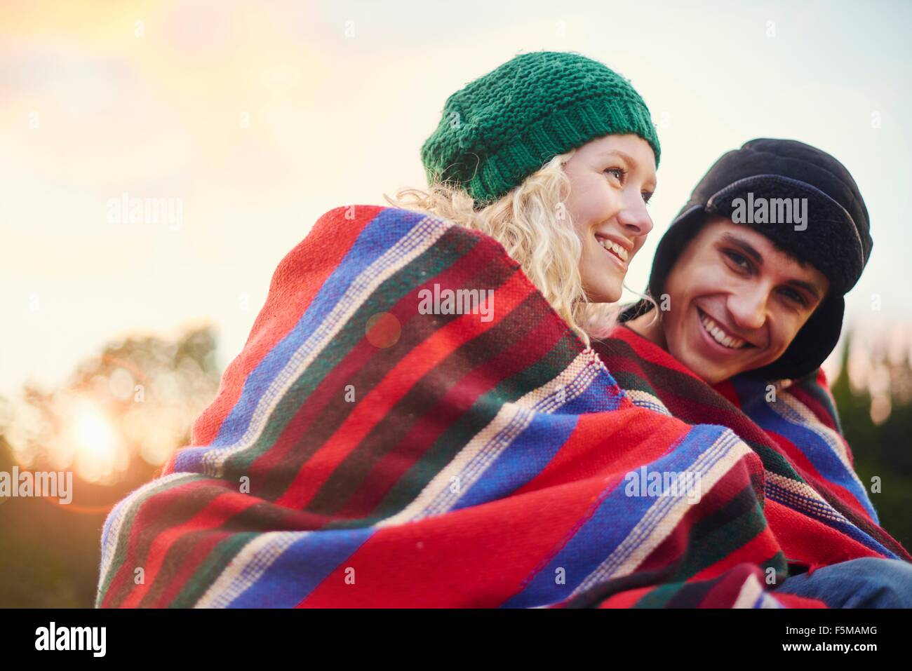 Portrait of romantic young camping couple wrapped in blanket Stock Photo