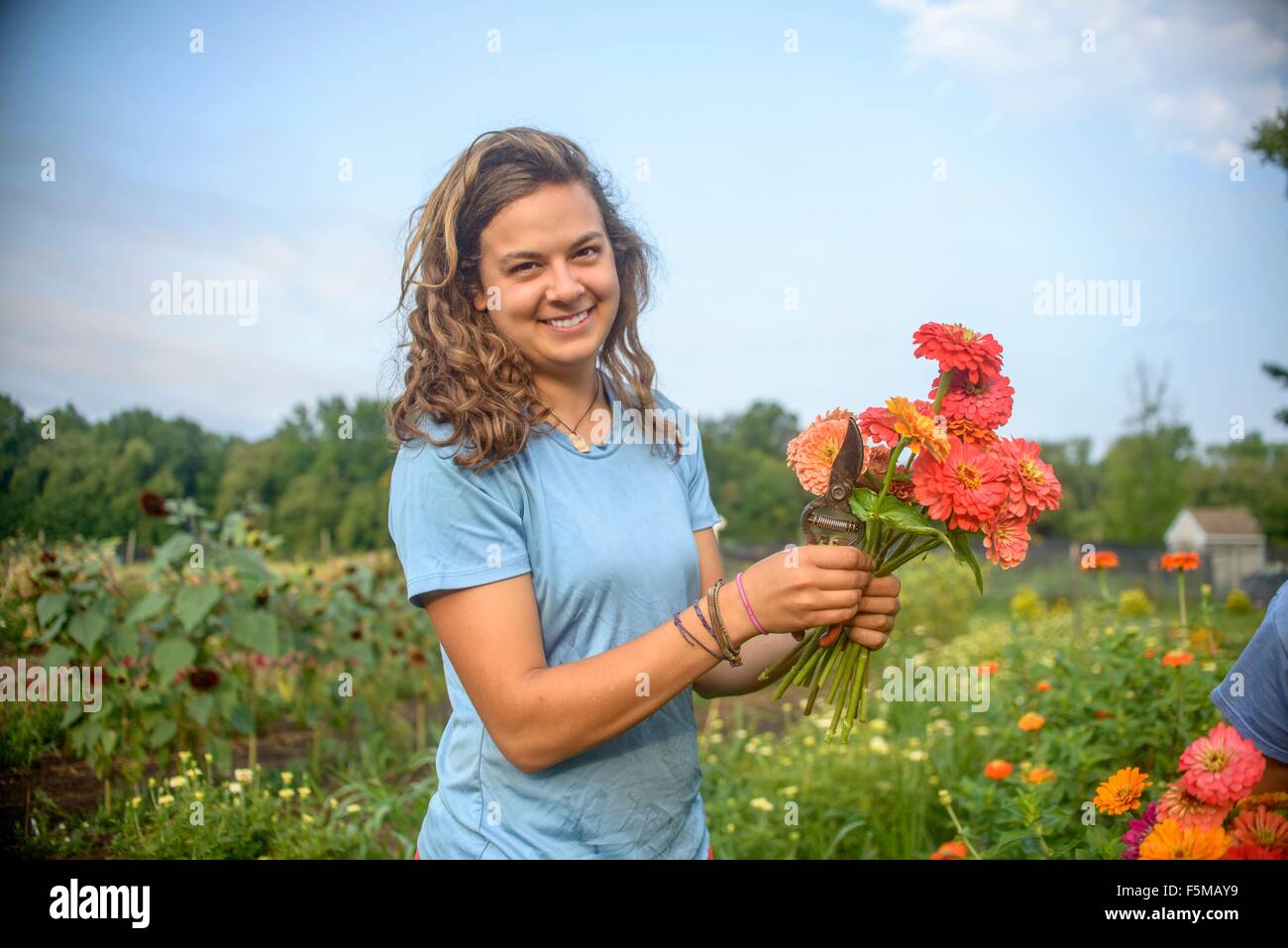 Portrait of female farm worker holding a bunch of fresh cut flowers Stock Photo