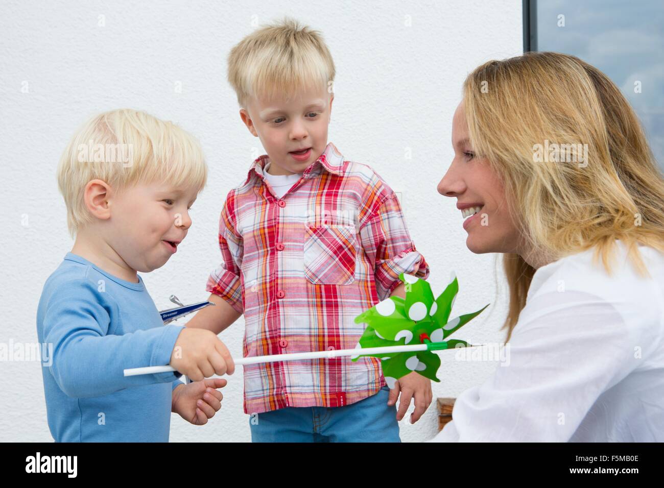 Mother and two young sons playing with pinwheel on patio Stock Photo ...