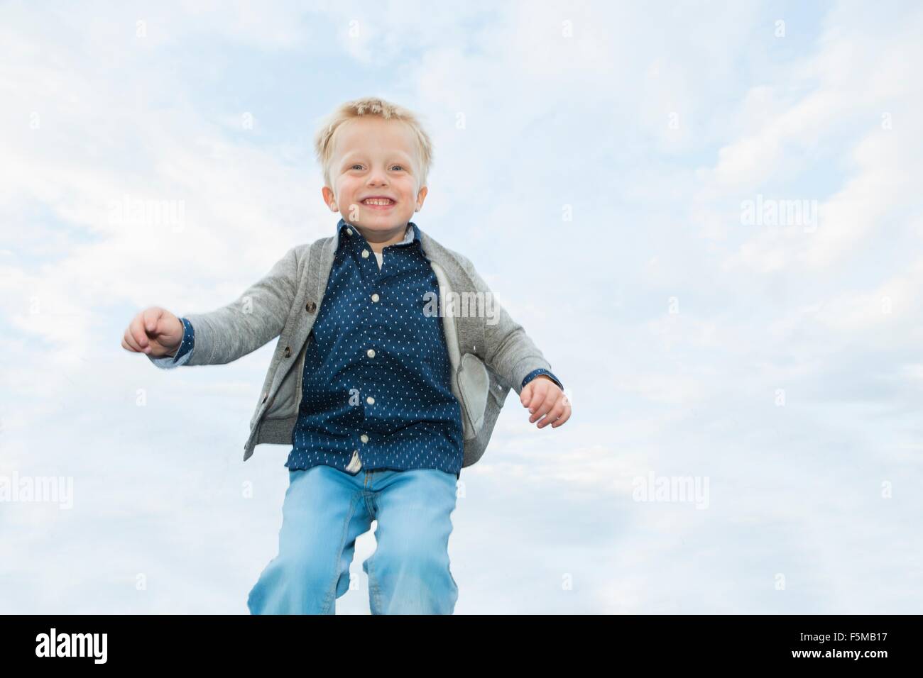 Happy boy mid air against sky Stock Photo