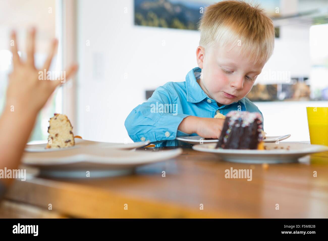 Male toddler eating cake at tea table Stock Photo