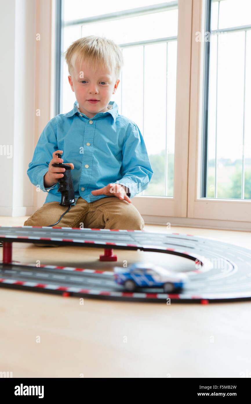 Boy playing with toy  racing cars on living room floor Stock Photo