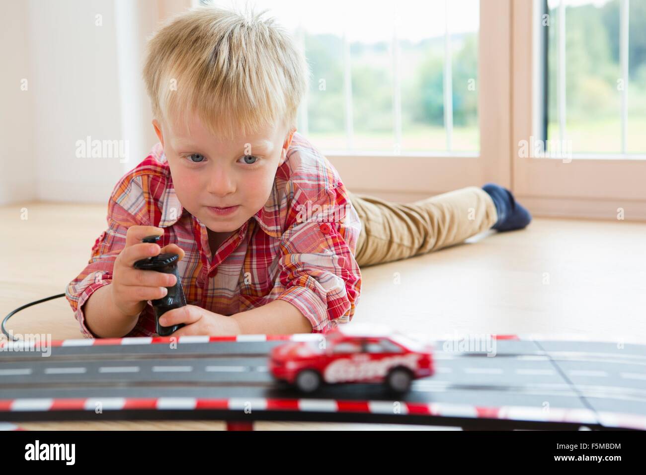 Boy playing with toy racing car on living room floor Stock Photo - Alamy