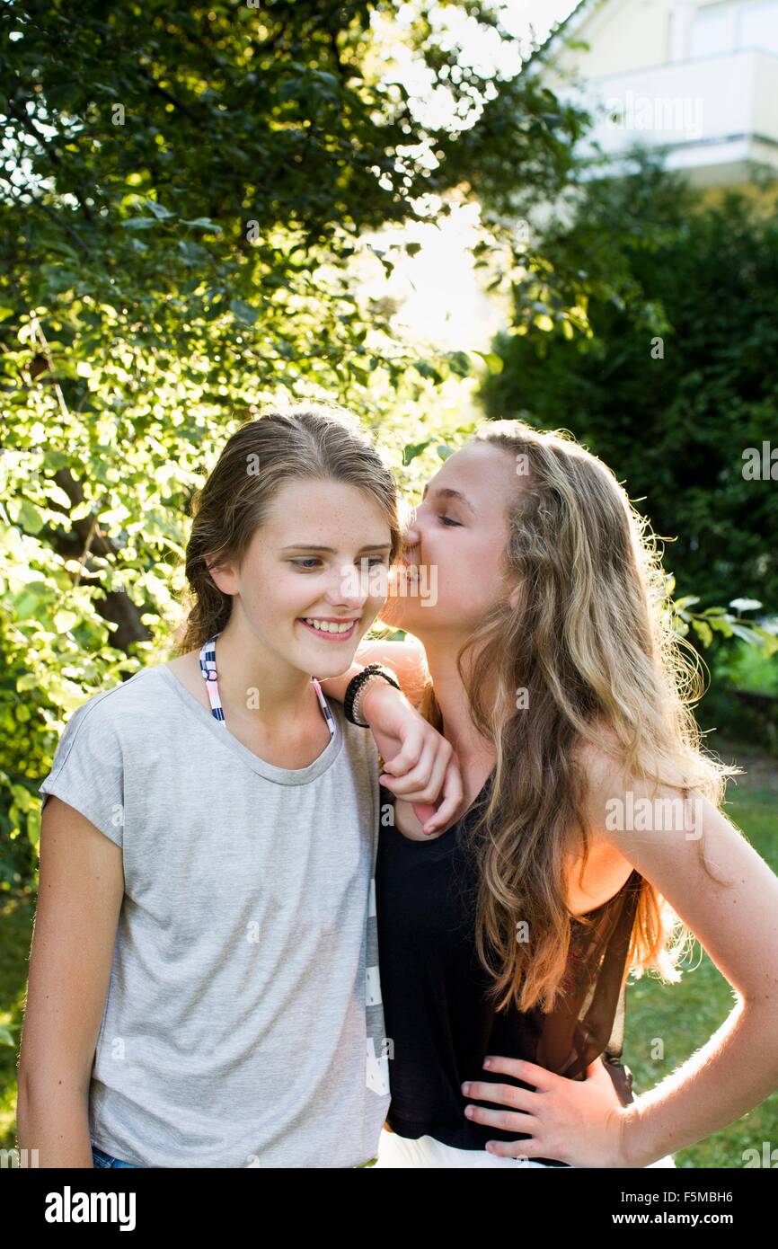 Two teenage girls whispering in garden Stock Photo - Alamy