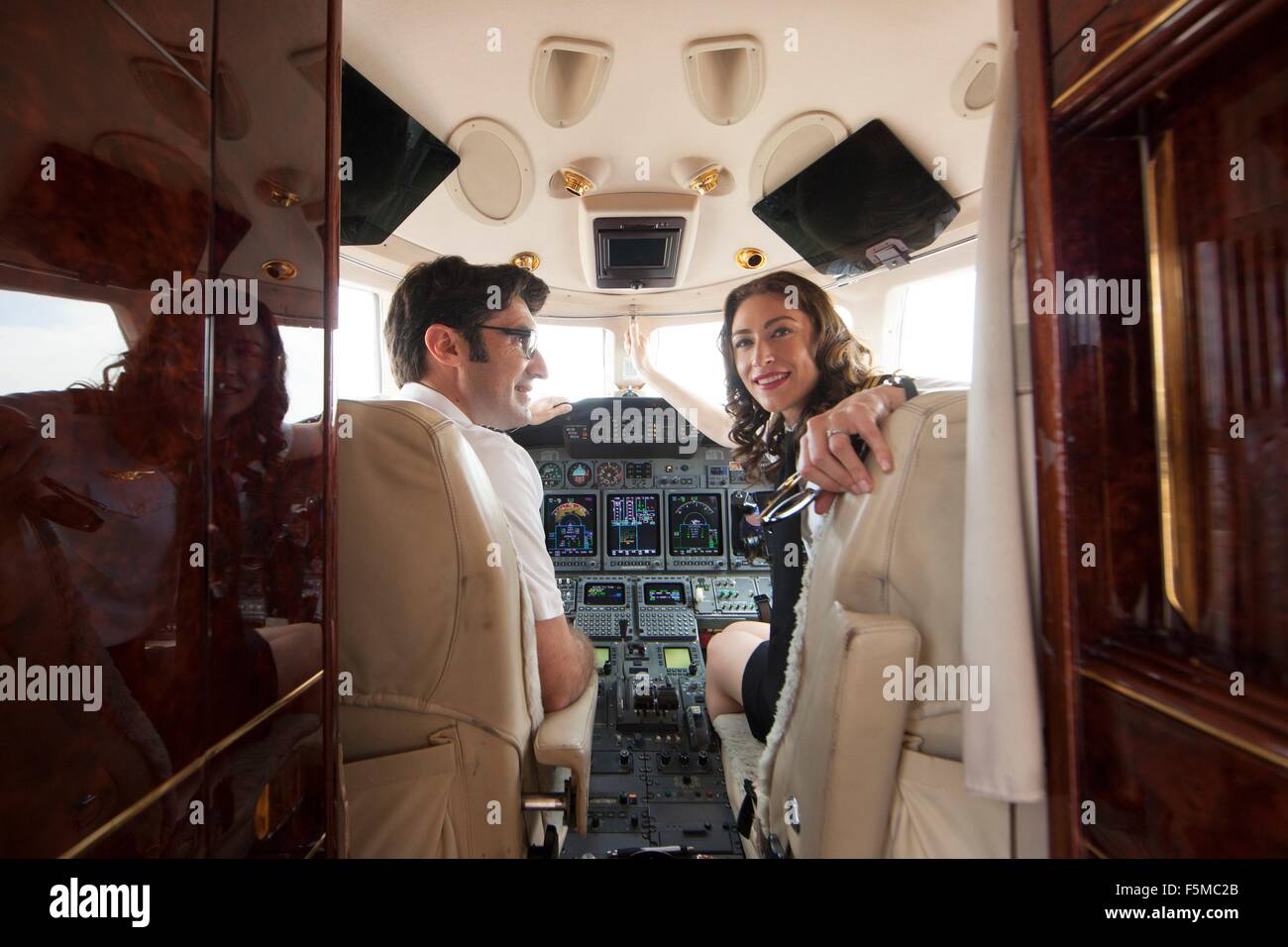Male and female pilot looking over her shoulder in cockpit of private jet Stock Photo