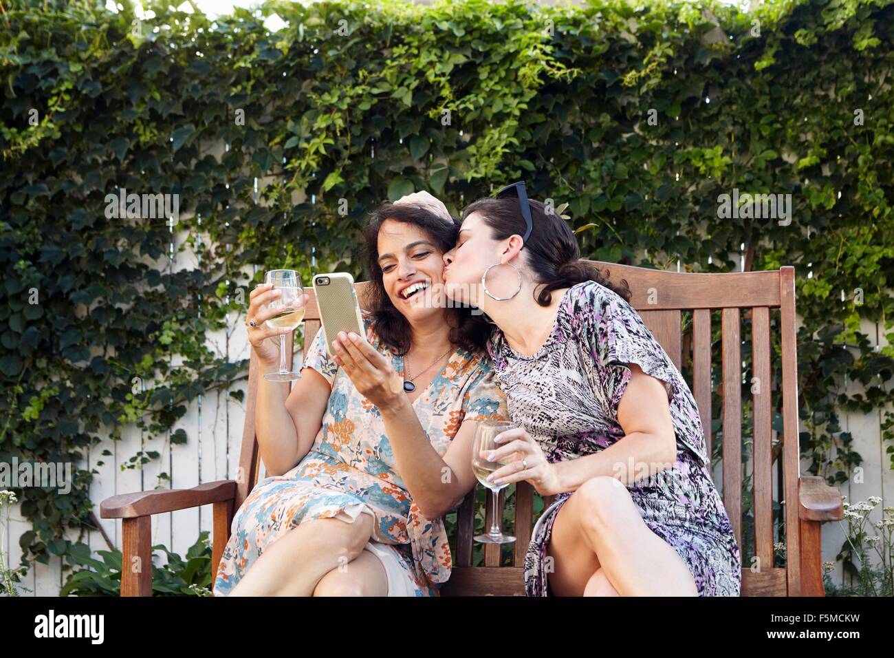 Two women posing for smartphone selfie on patio Stock Photo