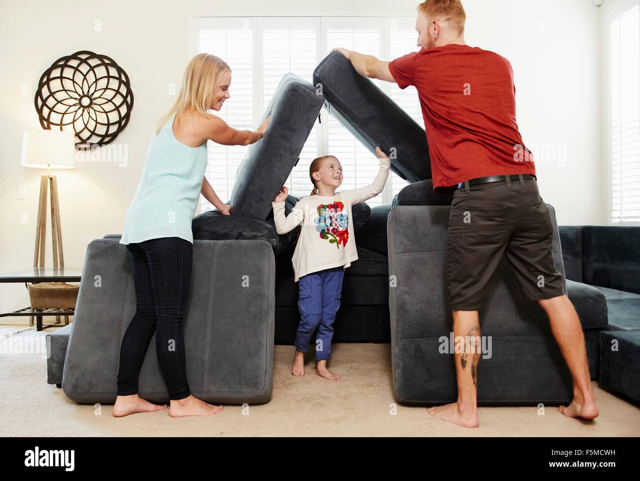 Family stacking cushions in living room Stock Photo