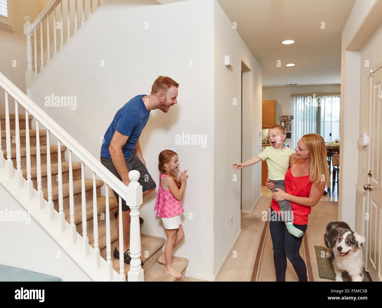 Family playing peek-a-boo on staircase at home Stock Photo