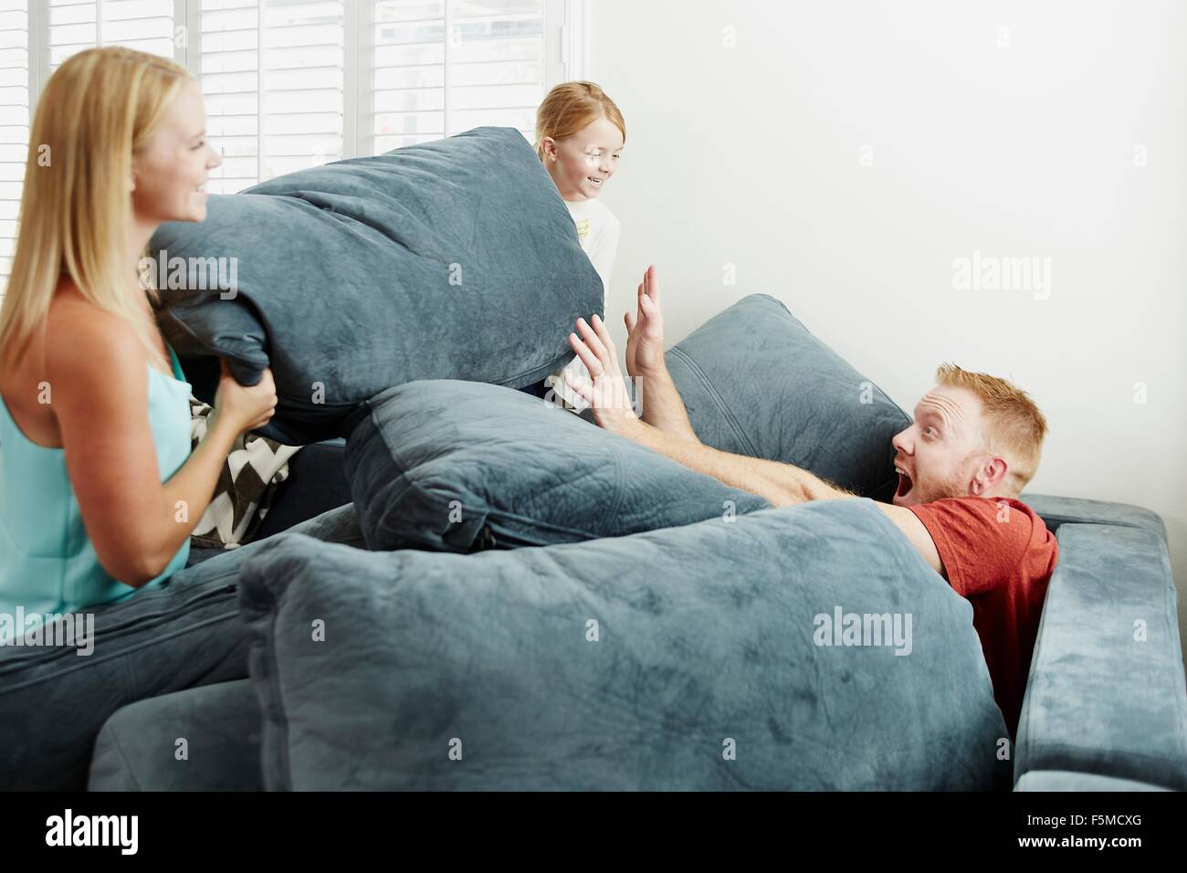 Family playing on pile of cushions in living room Stock Photo