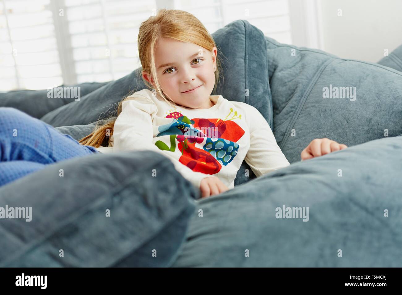 Girl lying on pile of cushions in living room Stock Photo