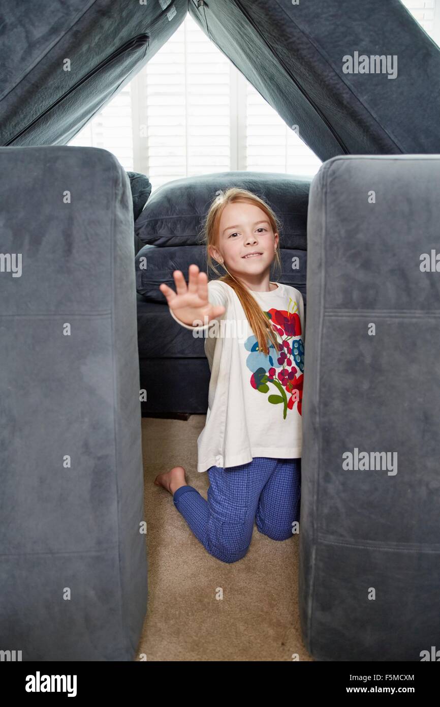 Girl stopping entry into tower of cushions in living room Stock Photo