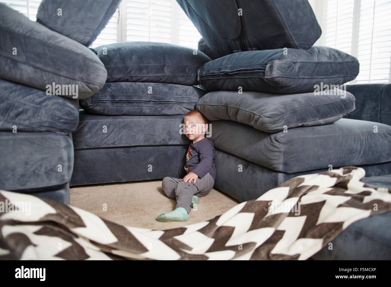Boy leaning against pile of cushions in living room Stock Photo