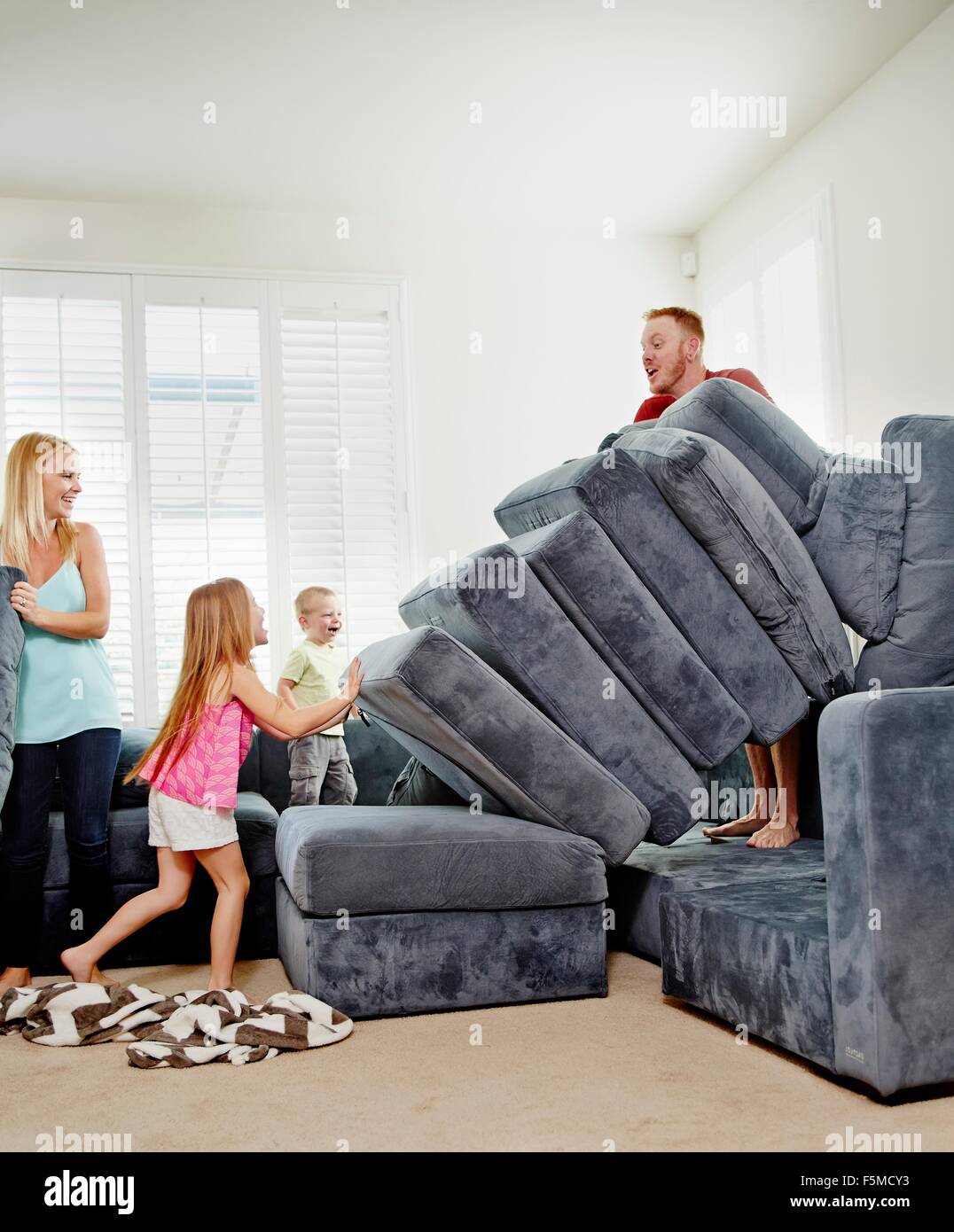 Family stacking cushions in living room Stock Photo