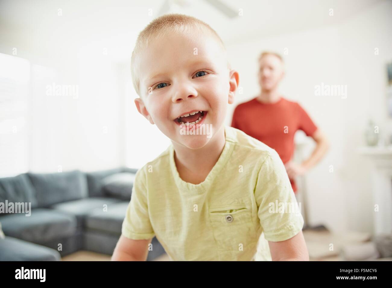 Boy smiling in living room, father in background Stock Photo