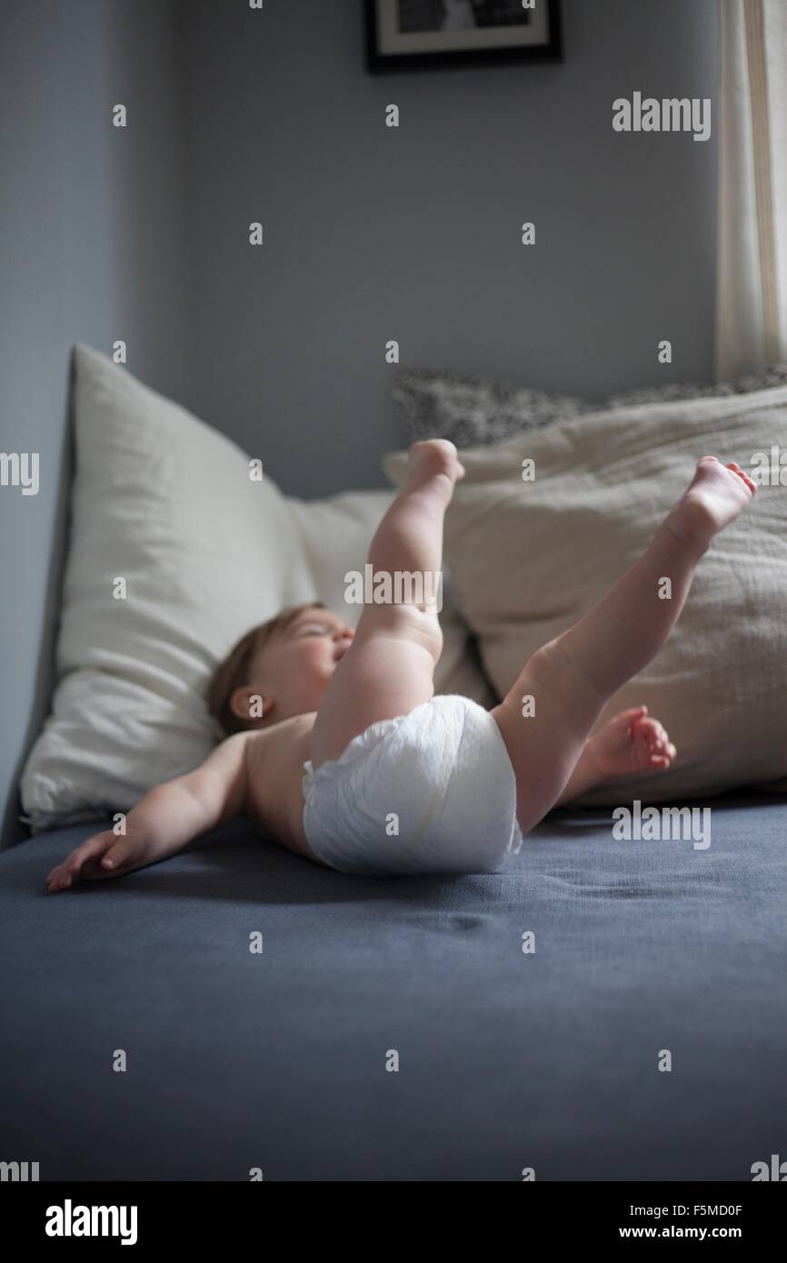 Baby boy wearing nappy lying on back legs raised Stock Photo