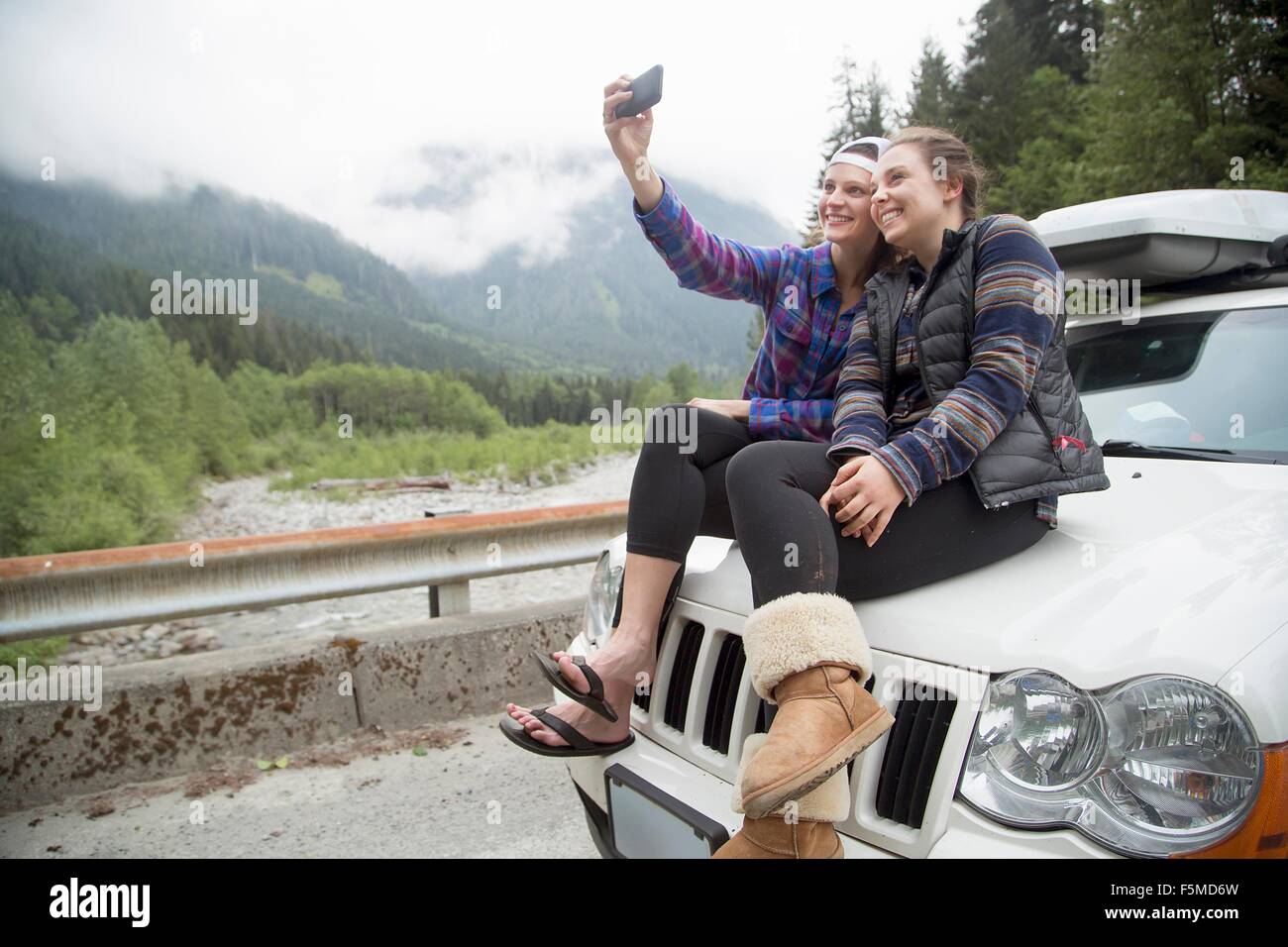 Hikers taking selfie with smartphone on bonnet of vehicle, Lake Blanco, Washington, USA Stock Photo