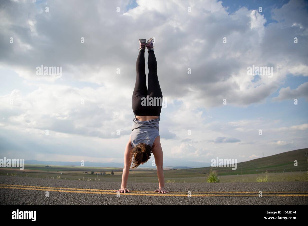 Woman doing handstand on country road, Lake Blanco, Washington, USA Stock Photo