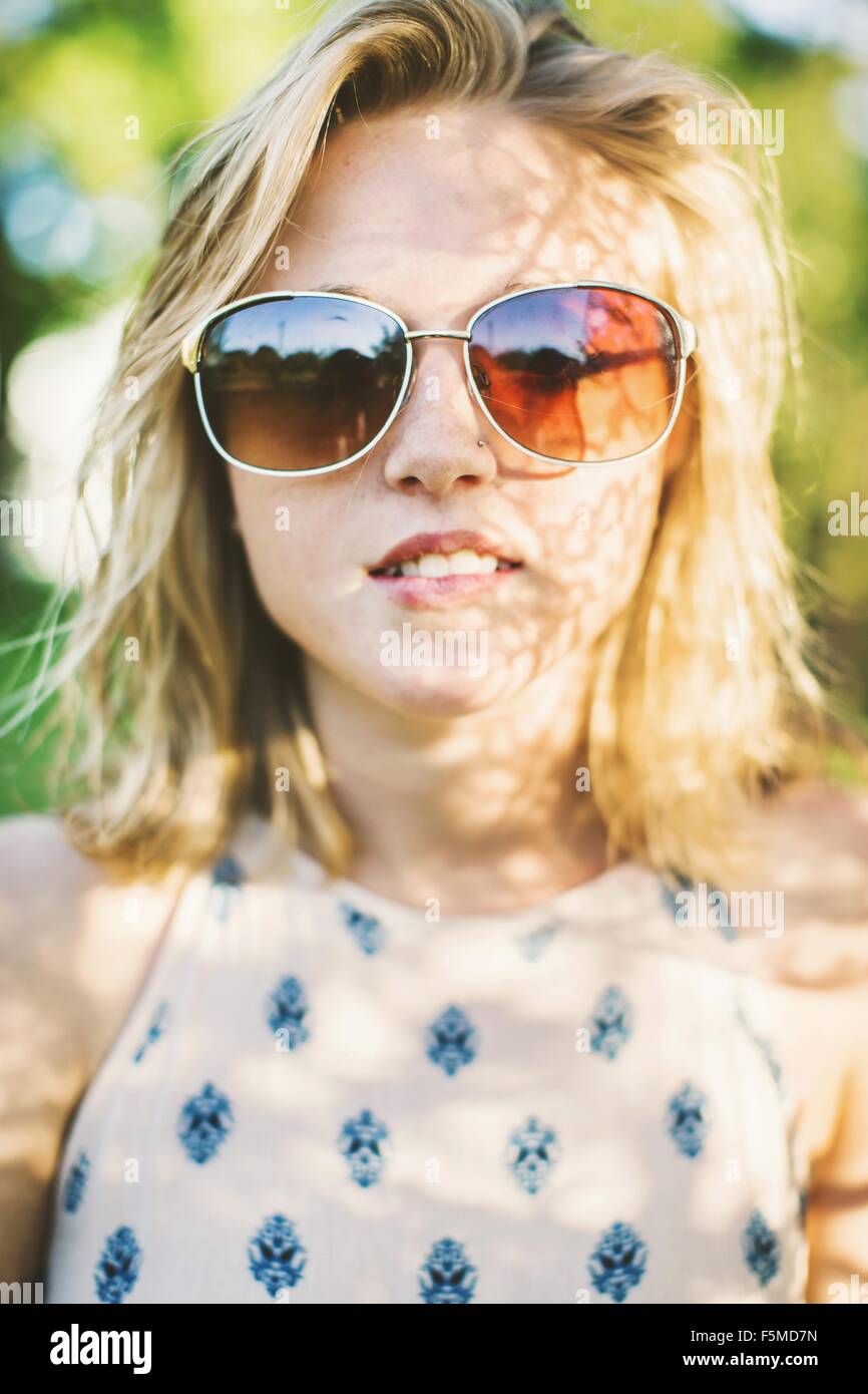 Close up portrait of young woman with wearing sunglasses looking at ...
