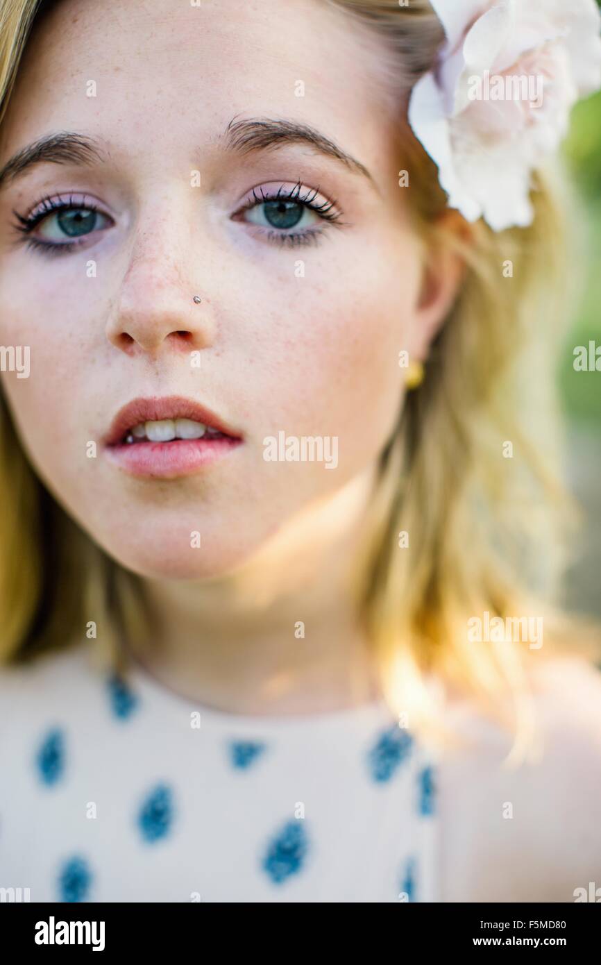 Close up portrait of young woman with nose stud, flower in hair looking at camera Stock Photo