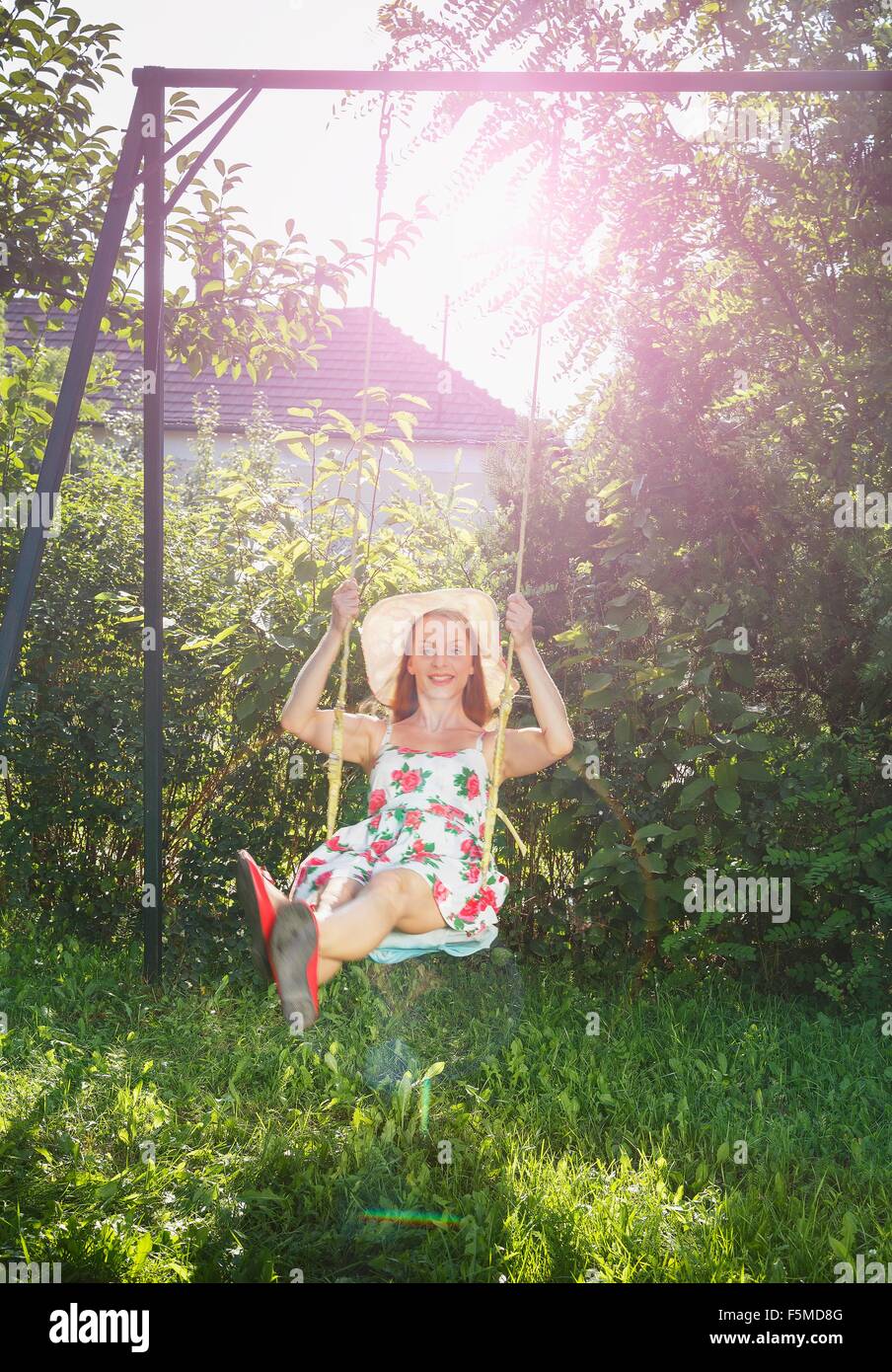 Mid adult woman swinging on garden swing Stock Photo