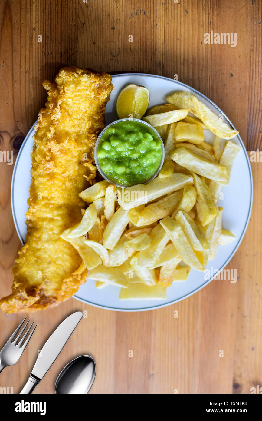 English Cod Fish and Chips with Mushy Peas in a plate on a table top Stock Photo
