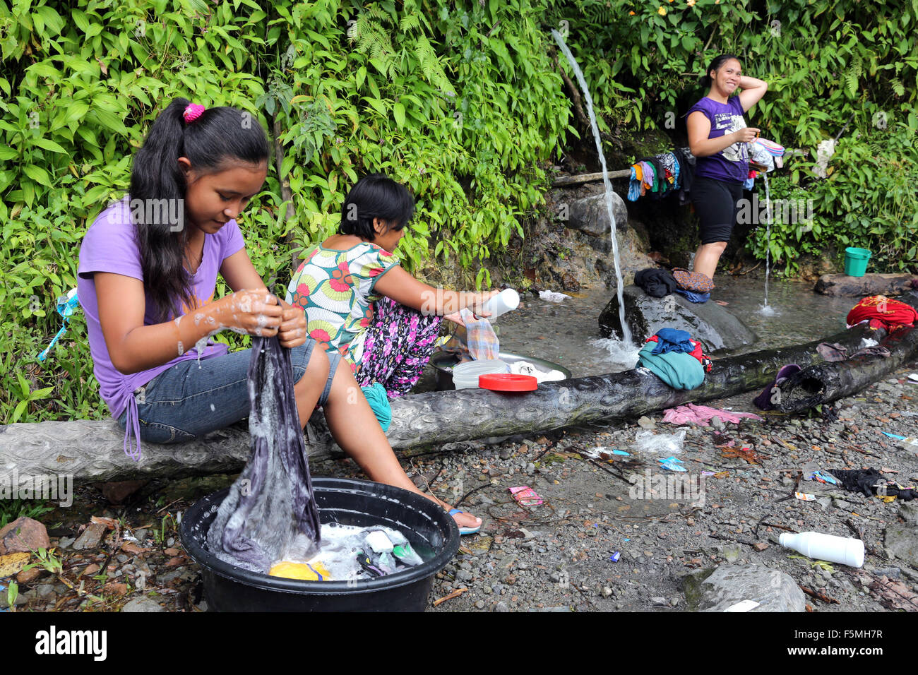 People washing cloth and bathing at a water source in the mountains