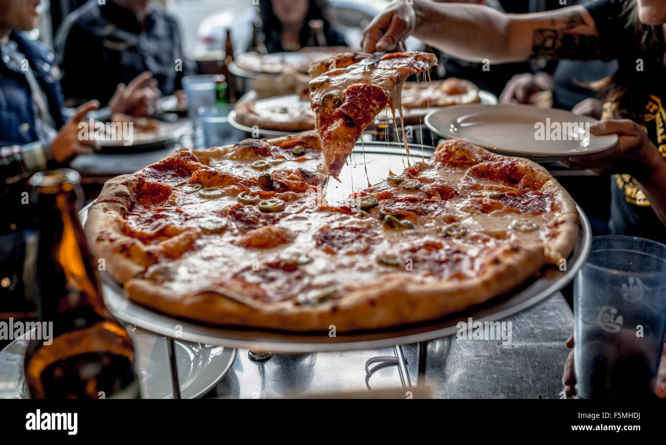 Slice of pizza being served at a restaurant Stock Photo