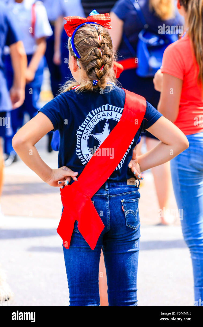 The sidewalk patriotic teenage girl show her support for Memorial day by wearing  a red sash and an American Legion t-shirt in d Stock Photo
