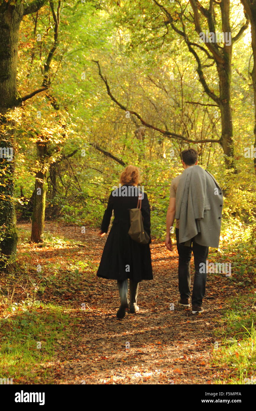 A  man and woman walking through woodland in Stanmore Country Park, near Wood Lane, Stanmore, London, England UK - October Stock Photo