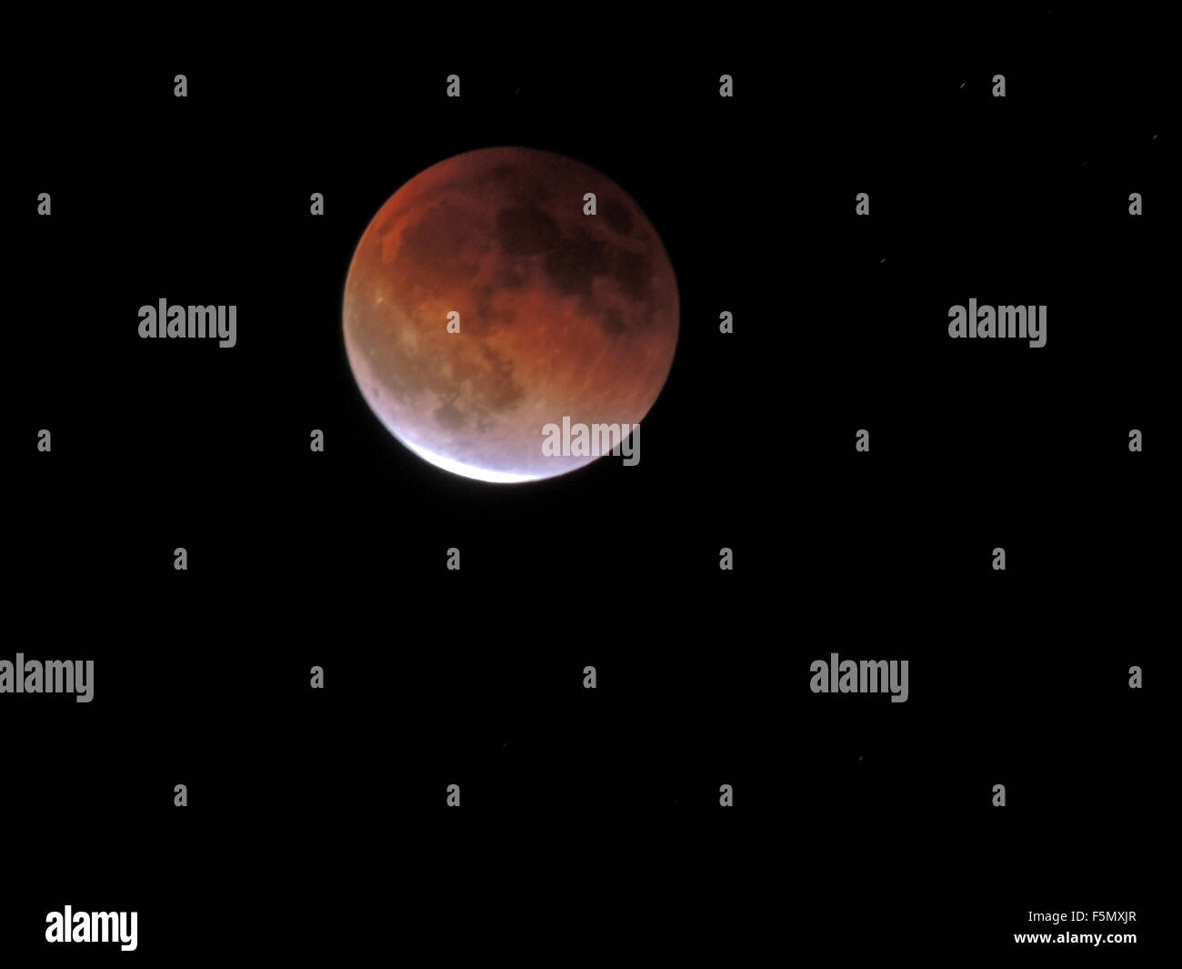 A wanning lunar eclipse reveals a bright sliver of the Blood moon. Stock Photo