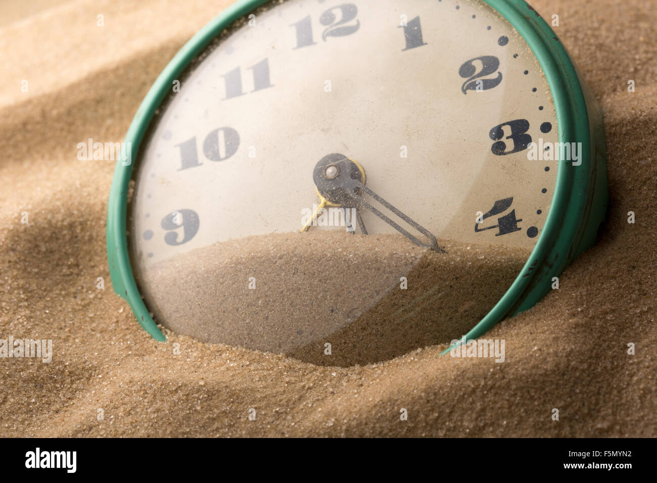 Old alarm clock in sand Stock Photo