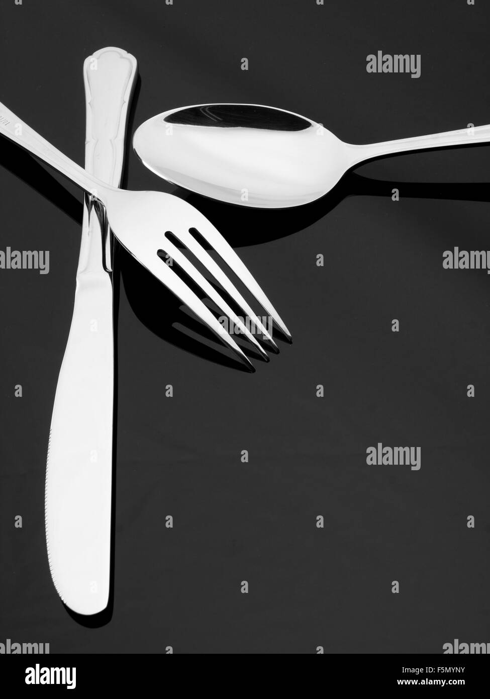 Side view of silver fork, knife and spoon on dark background Stock