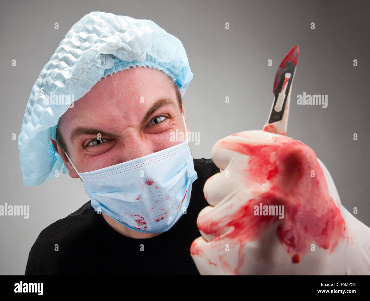 Mad mental sick blood soiled surgeon with knife Stock Photo