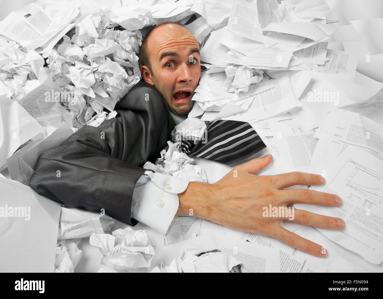 Businessman sinking in heap of documents and asking for help Stock Photo