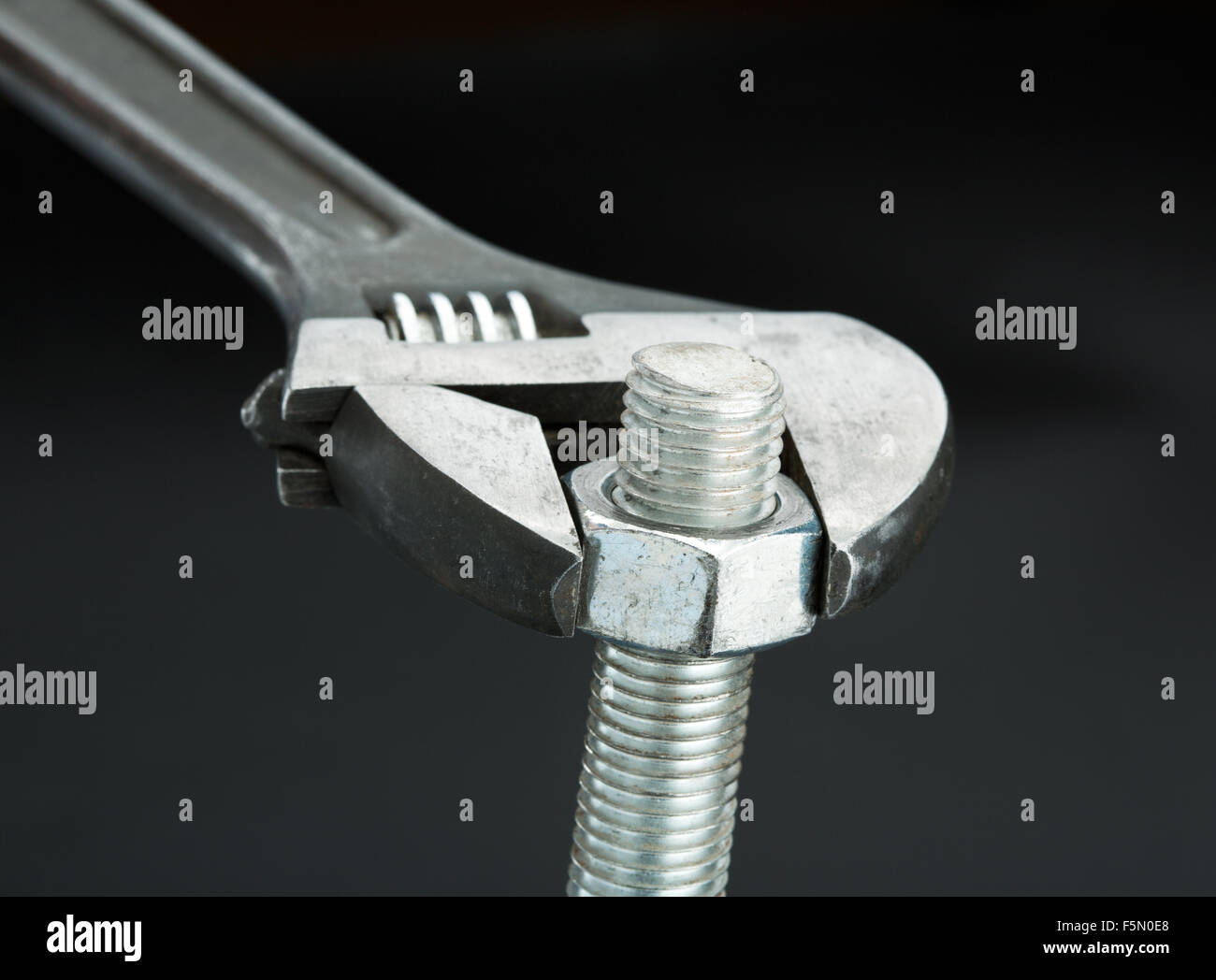 Macro shot of a bolt and a wrench isolated on black Stock Photo