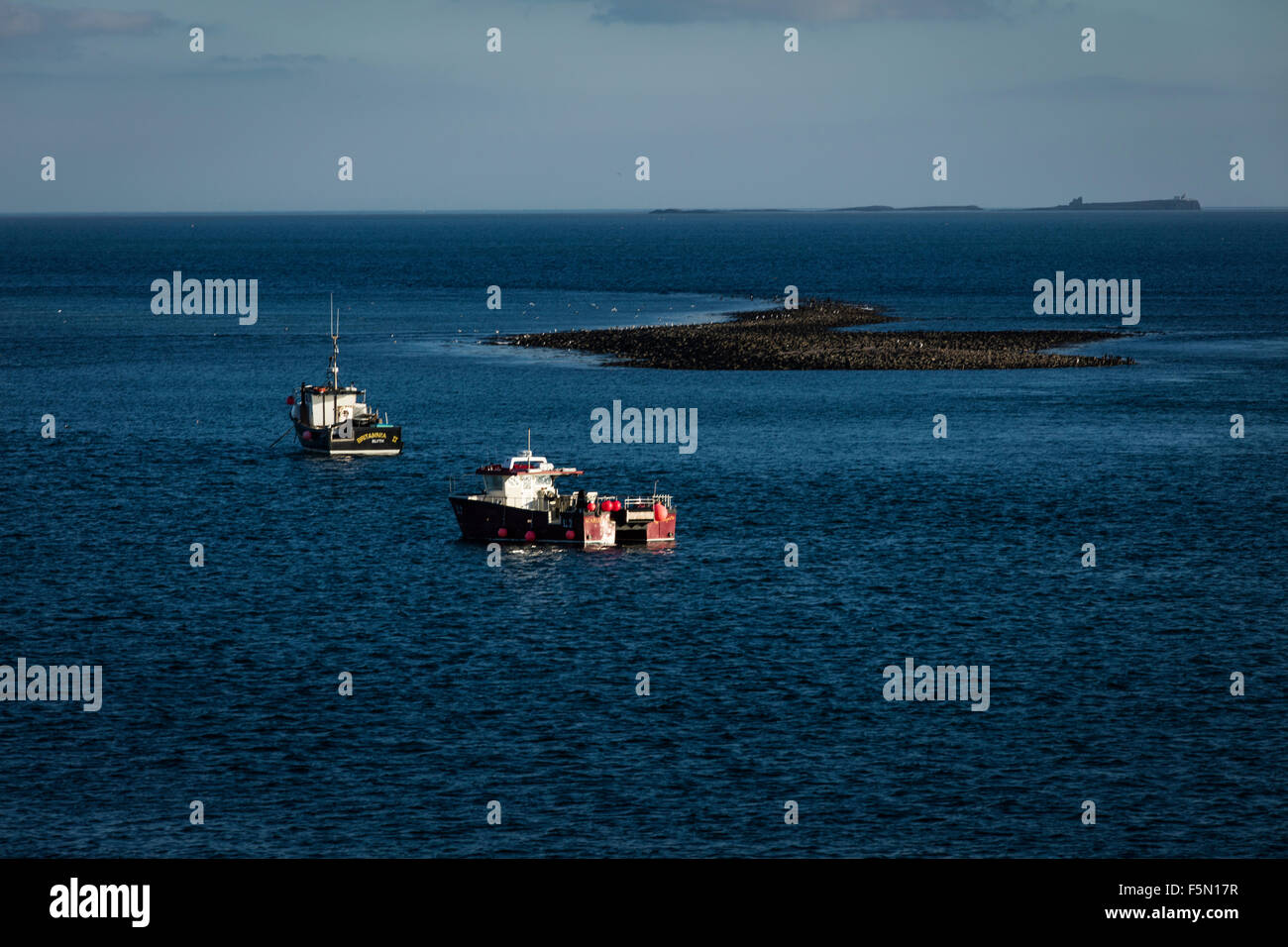 Boats in the sea looking towards the Farne Islands from the Holy Island at high tide Stock Photo
