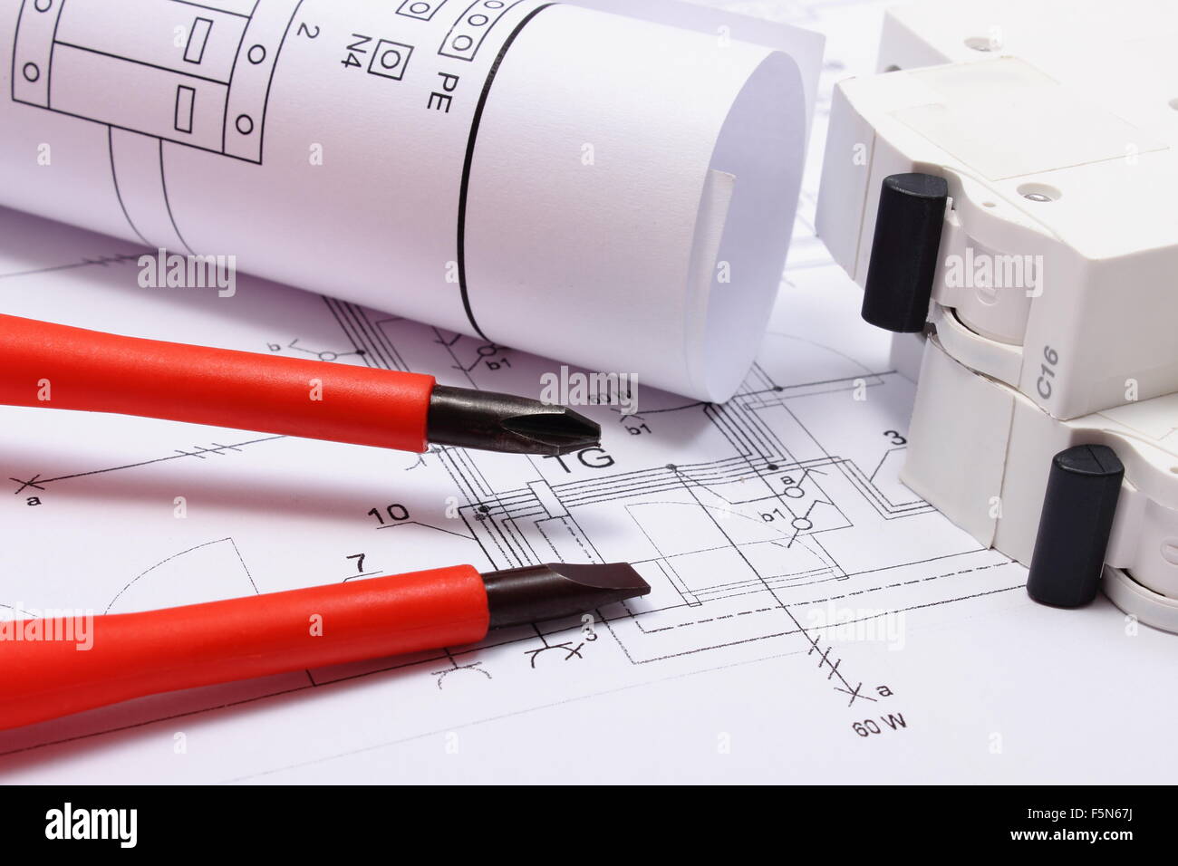 Rolls of electrical diagrams, electric fuse and red screwdrivers lying ...